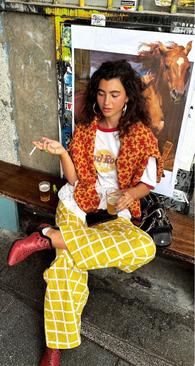 Yellow checked trousers, red patterned knit and red boots on a street bench